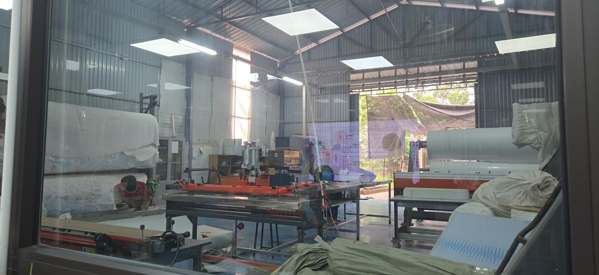 Xưởng gia công nhìn từ văn phòng, máy nối nhiệt và bàn hàn gân
